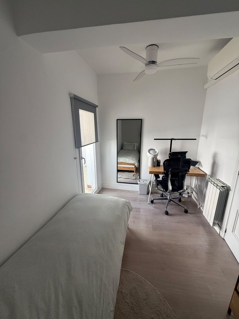 Vista general de la habitación con la cama, la ventana, el espejo y el escritorio