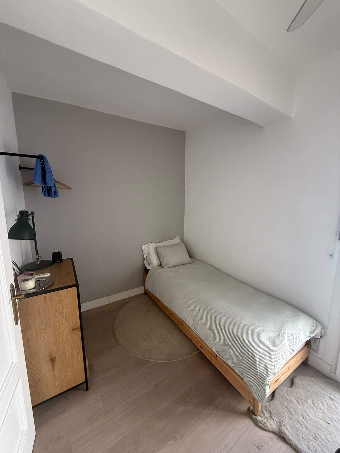 Dormitorio con la cama de pino, la cómoda de madera y la barra para colgar la ropa